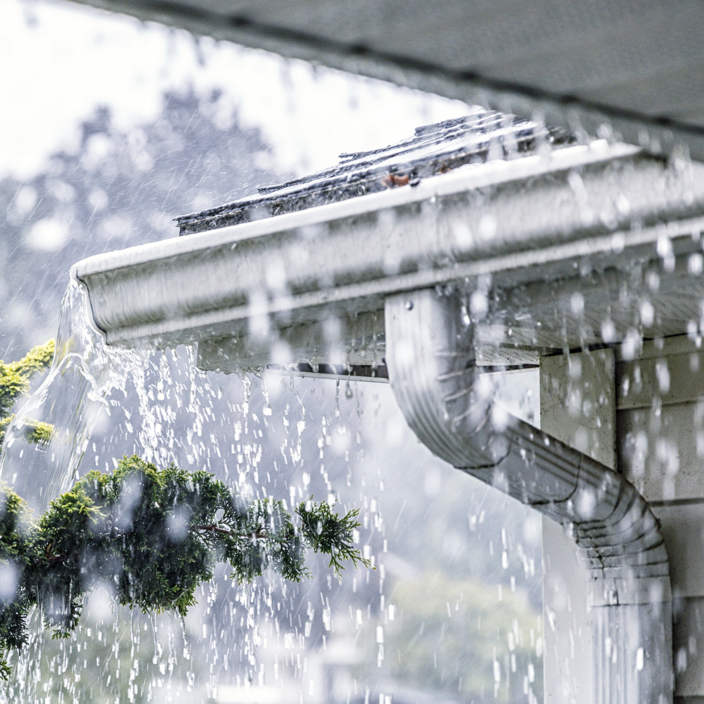 A close-up of water overflowing from rain gutters during a heavy downpour, highlighting the importance of maintenance discussed in the LA County water FAQ.