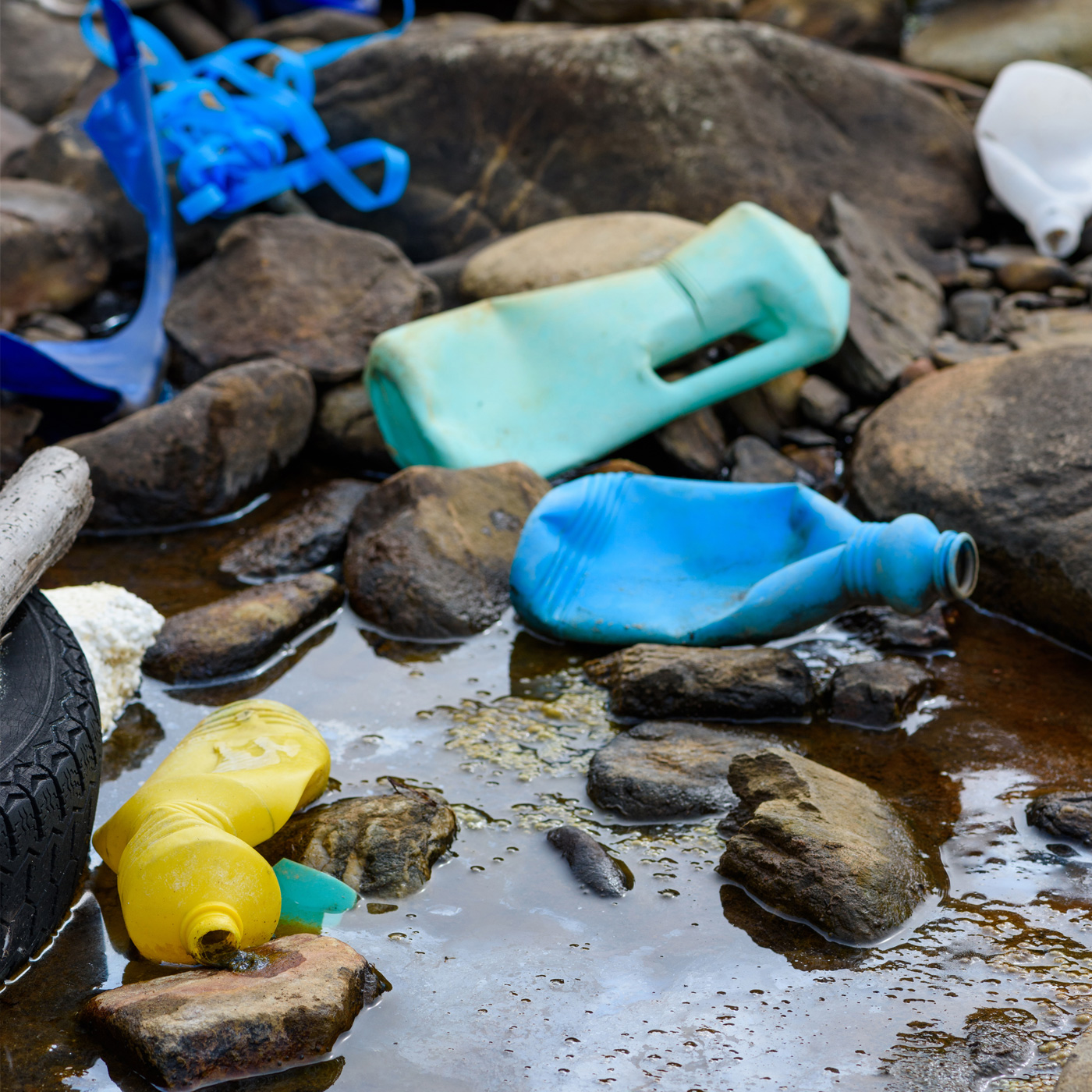 A photo of discarded plastic bottles and debris in a rocky area, highlighting the environmental challenges and pollution prevention tips discussed in the LA County water FAQ.