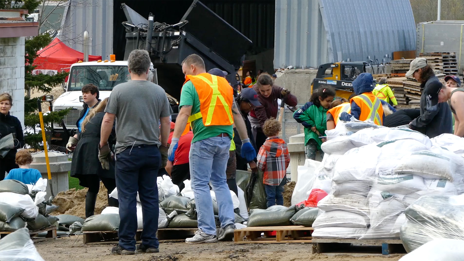 A group of community volunteers and staff working together to fill and stack sandbags, a key flood preparation activity highlighted in the LA County water FAQ.