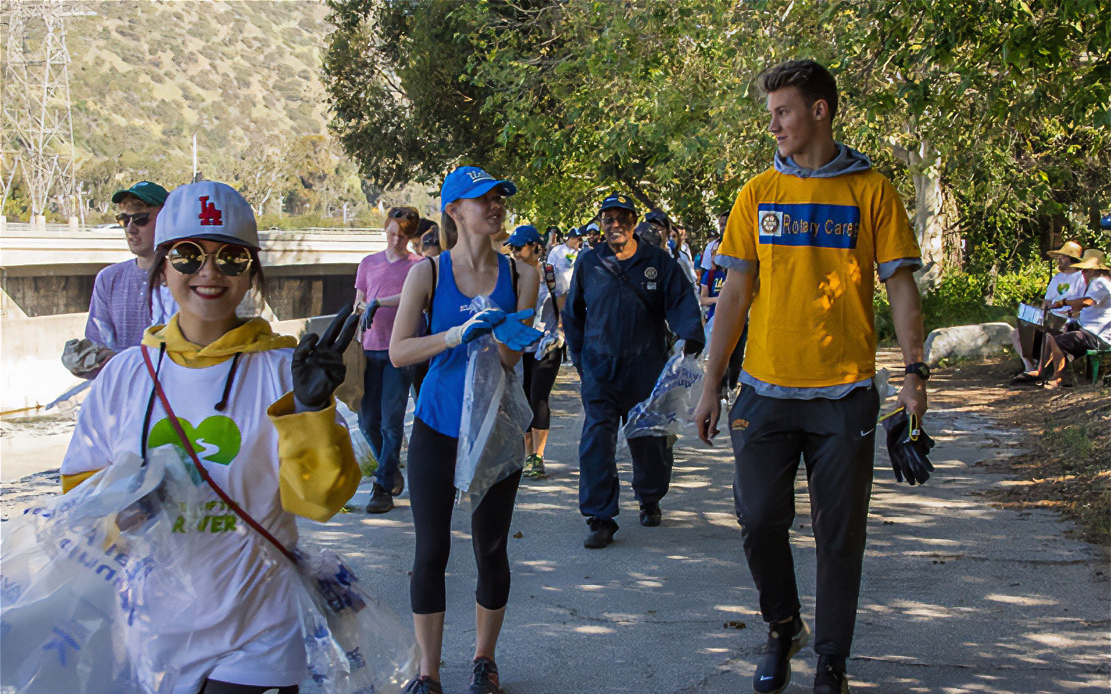 Volunteers wearing gloves and carrying trash bags during a cleanup event along the Los Angeles River