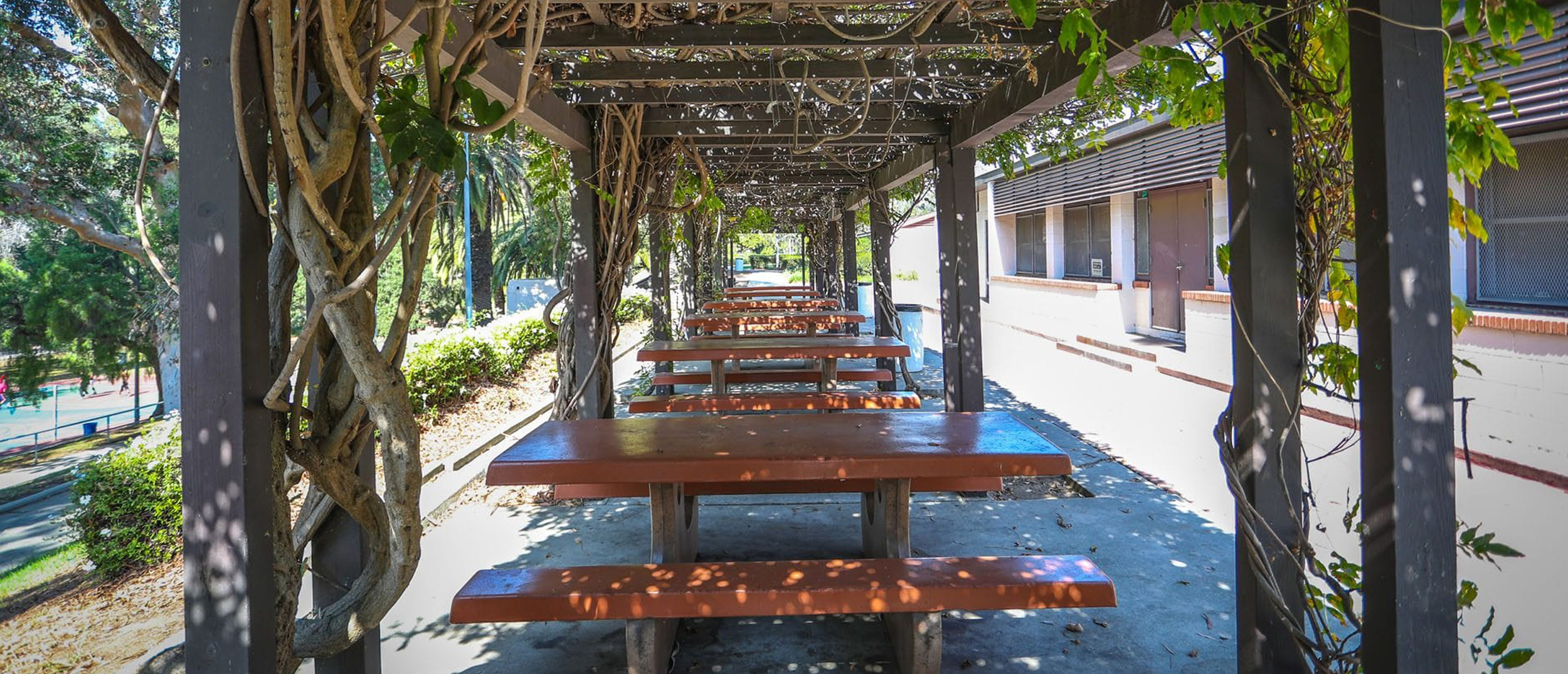 A view of the shaded picnic tables and benches under a wooden pergola at Ladera Park, one of the region's Multi-benefit water projects featuring underground stormwater capture and treatment.