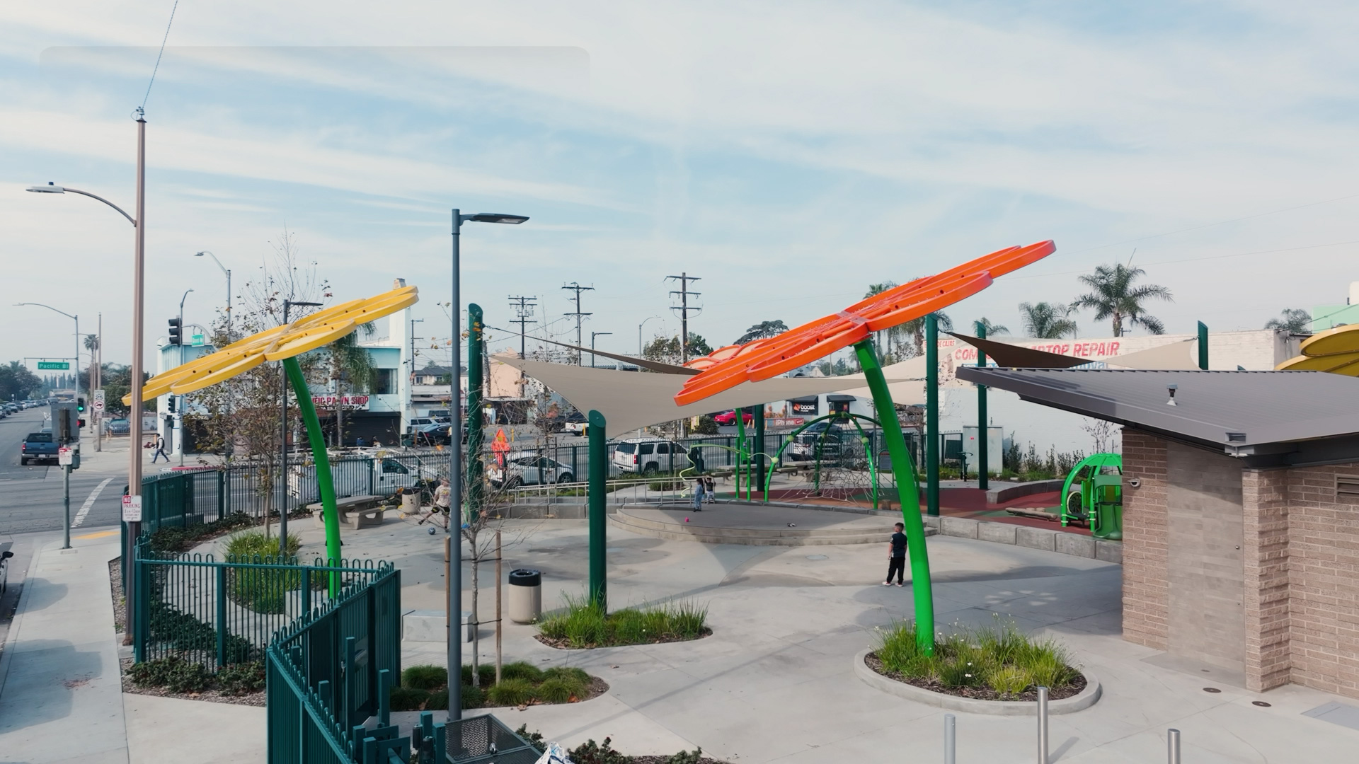 A wide view of the modern playground at Nogales Park featuring colorful green and orange shade structures and play equipment.