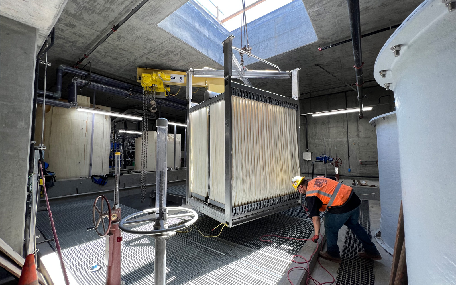 A worker at the City of Santa Monica’s Sustainable water infrastructure project inspecting industrial filtration equipment to ensure efficient water treatment.