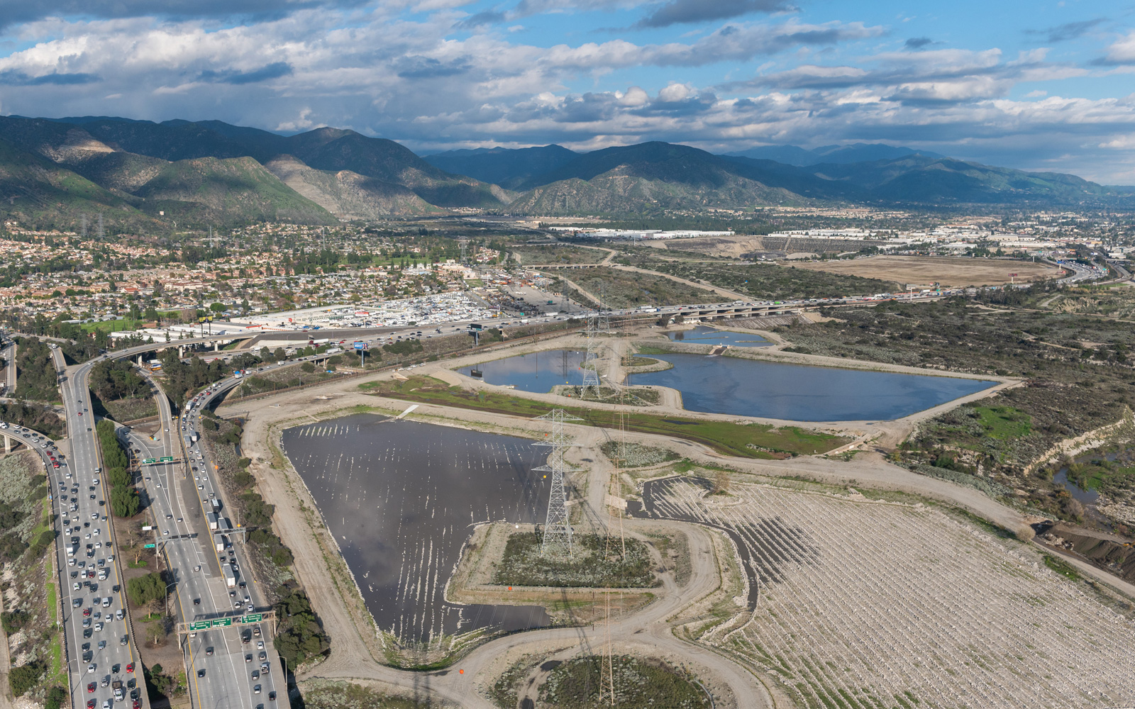 Photo of Aerial view of the Santa Fe Spreading Grounds showing water basins adjacent to a highway and mountains