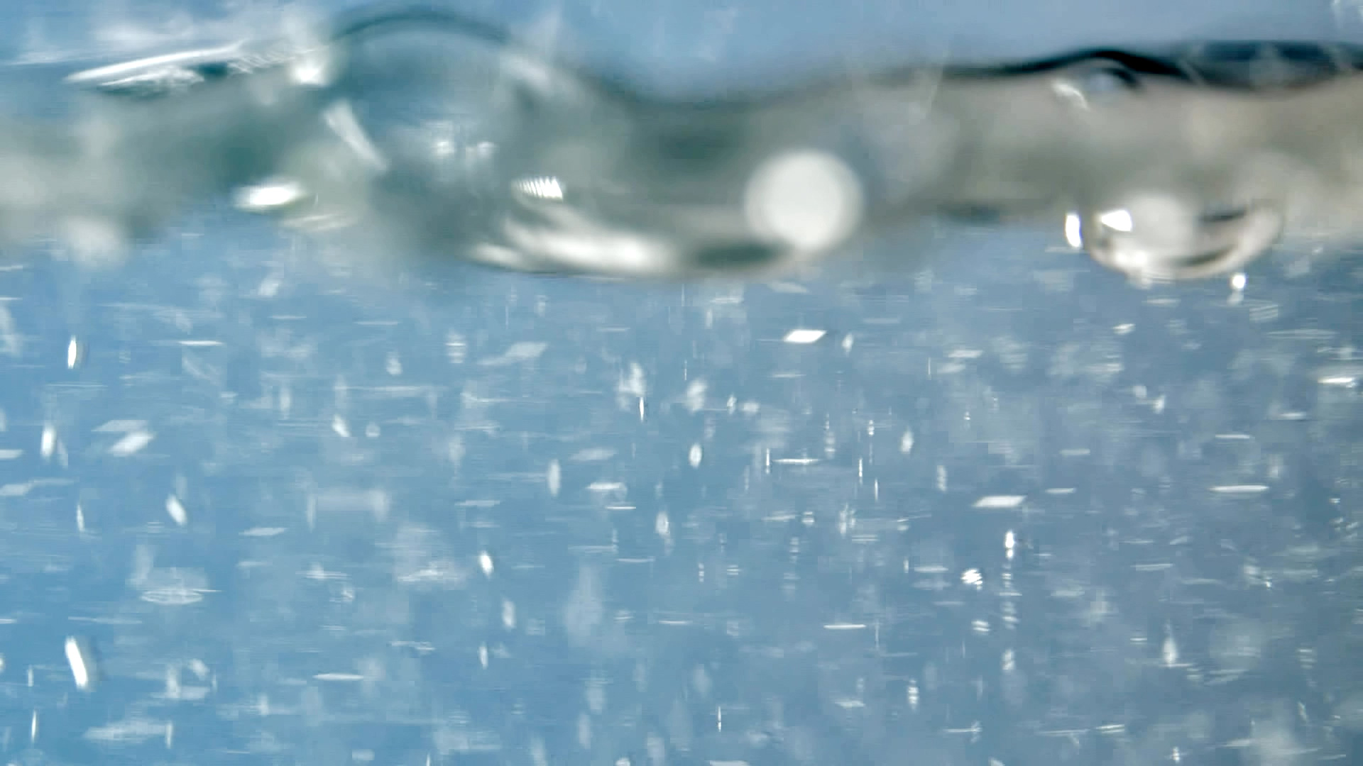 Close-up of water with bubbles and light refraction inside a glass